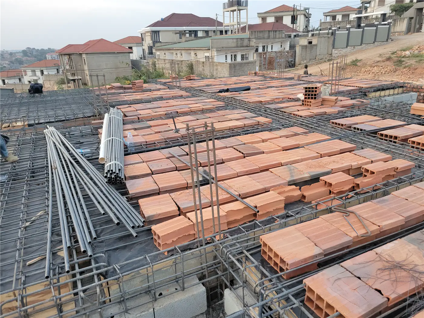 Laying hollow clay blocks and reinforcement steel bars for the suspended slab at Nsasa-Kira