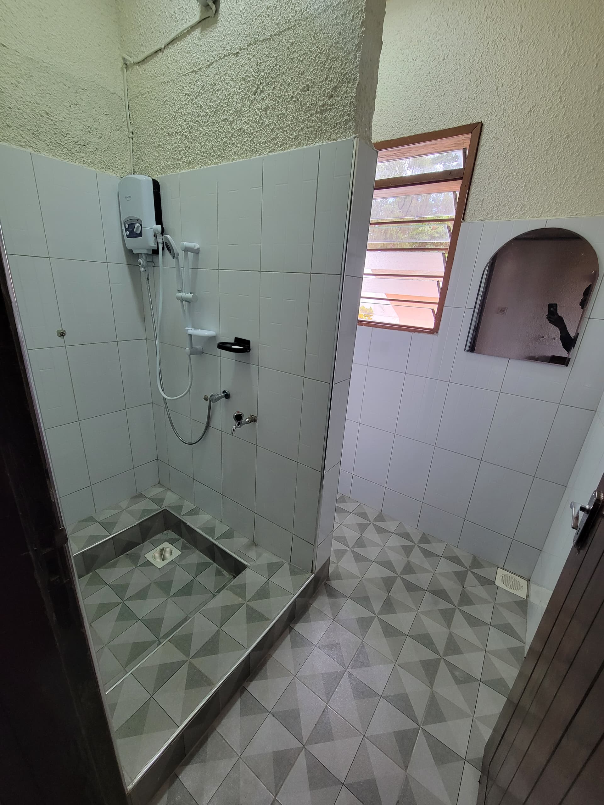 Completed bathroom overview showing new toilet fixtures and full wall tiling at Xavier House Nsambya