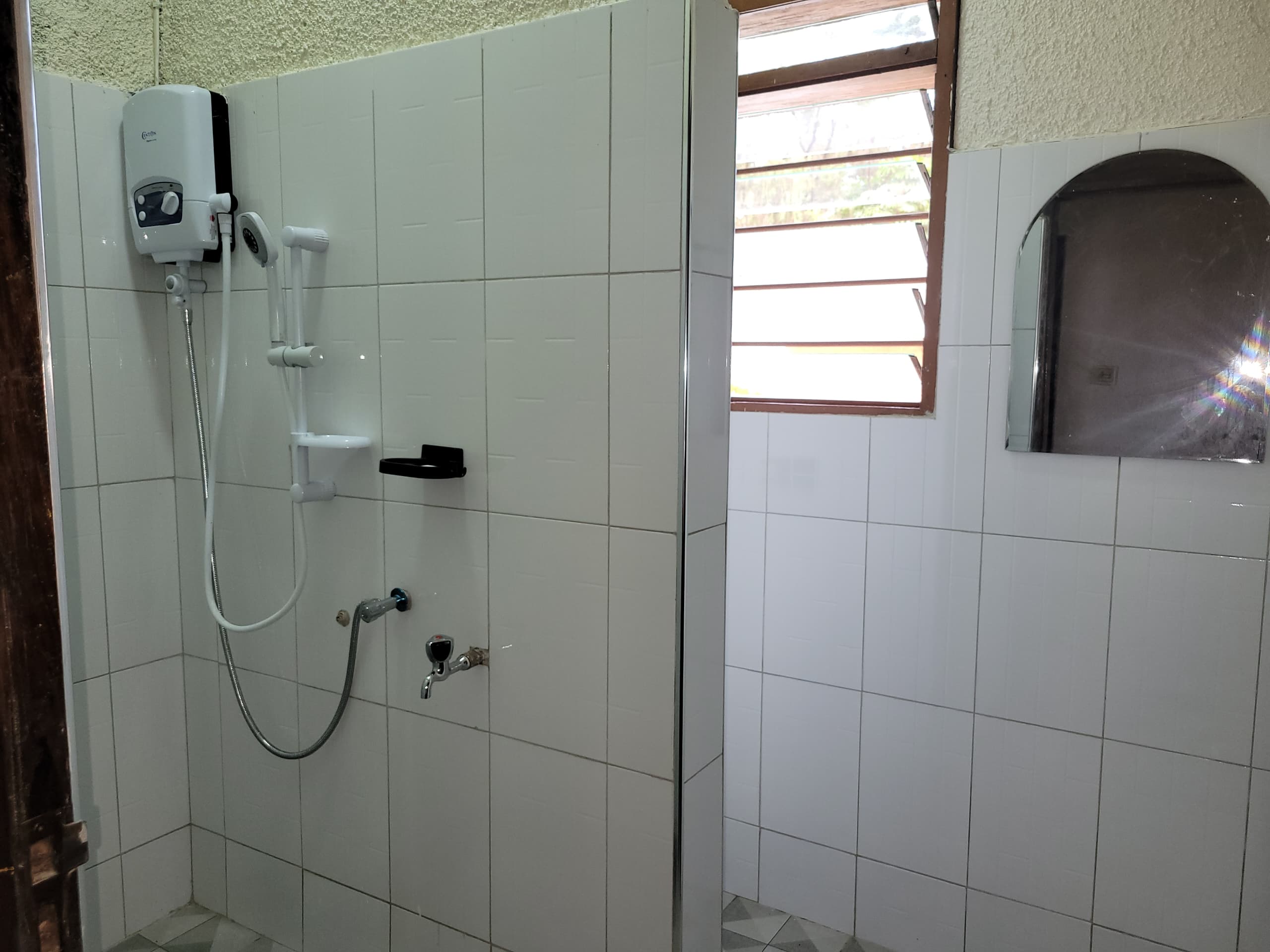 Completed shower area with water heater hand basin and mirror installed at Xavier House Nsambya