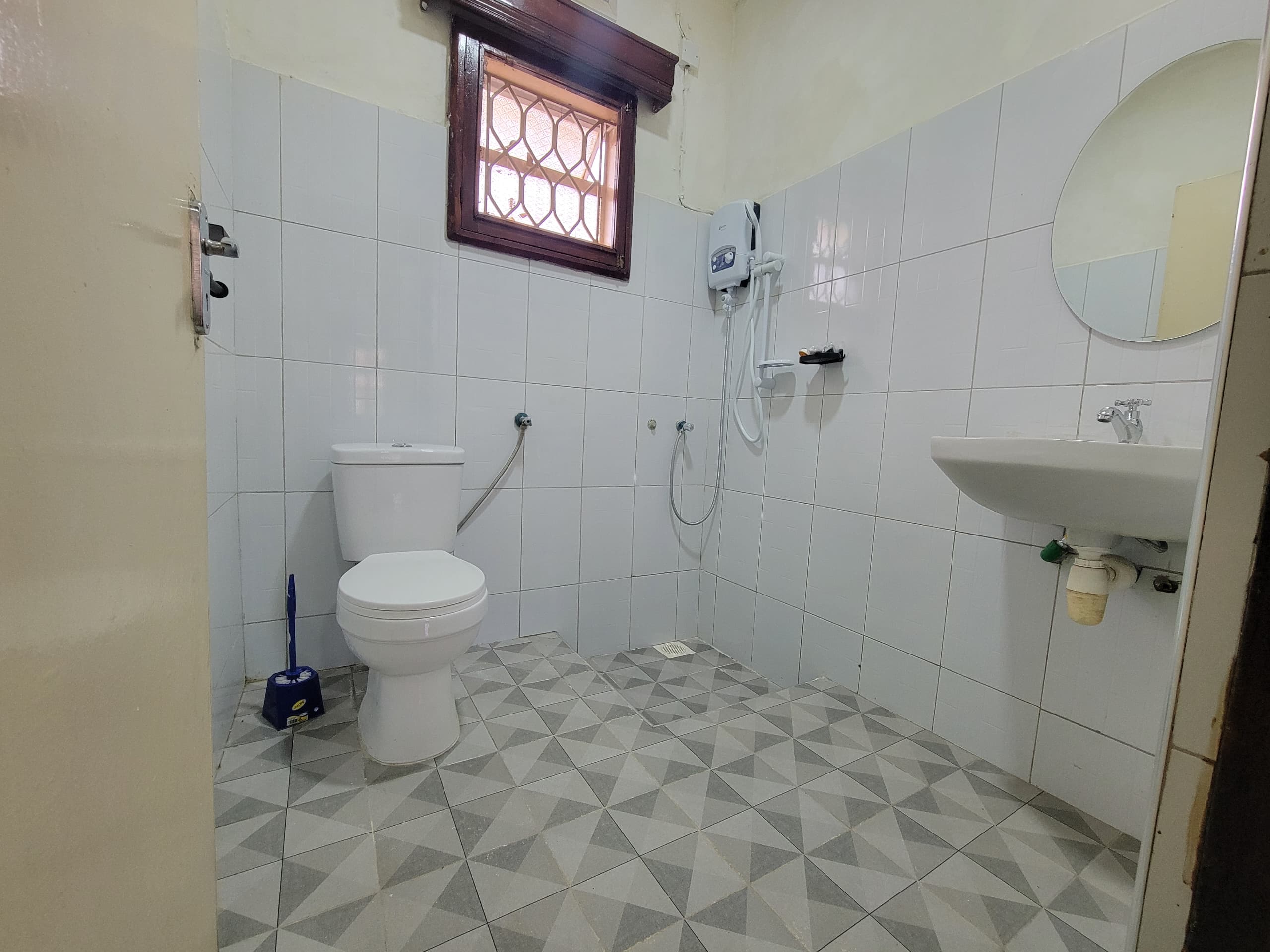Completed toilet installation with new white ceramic toilet and tiled walls at Xavier House Nsambya