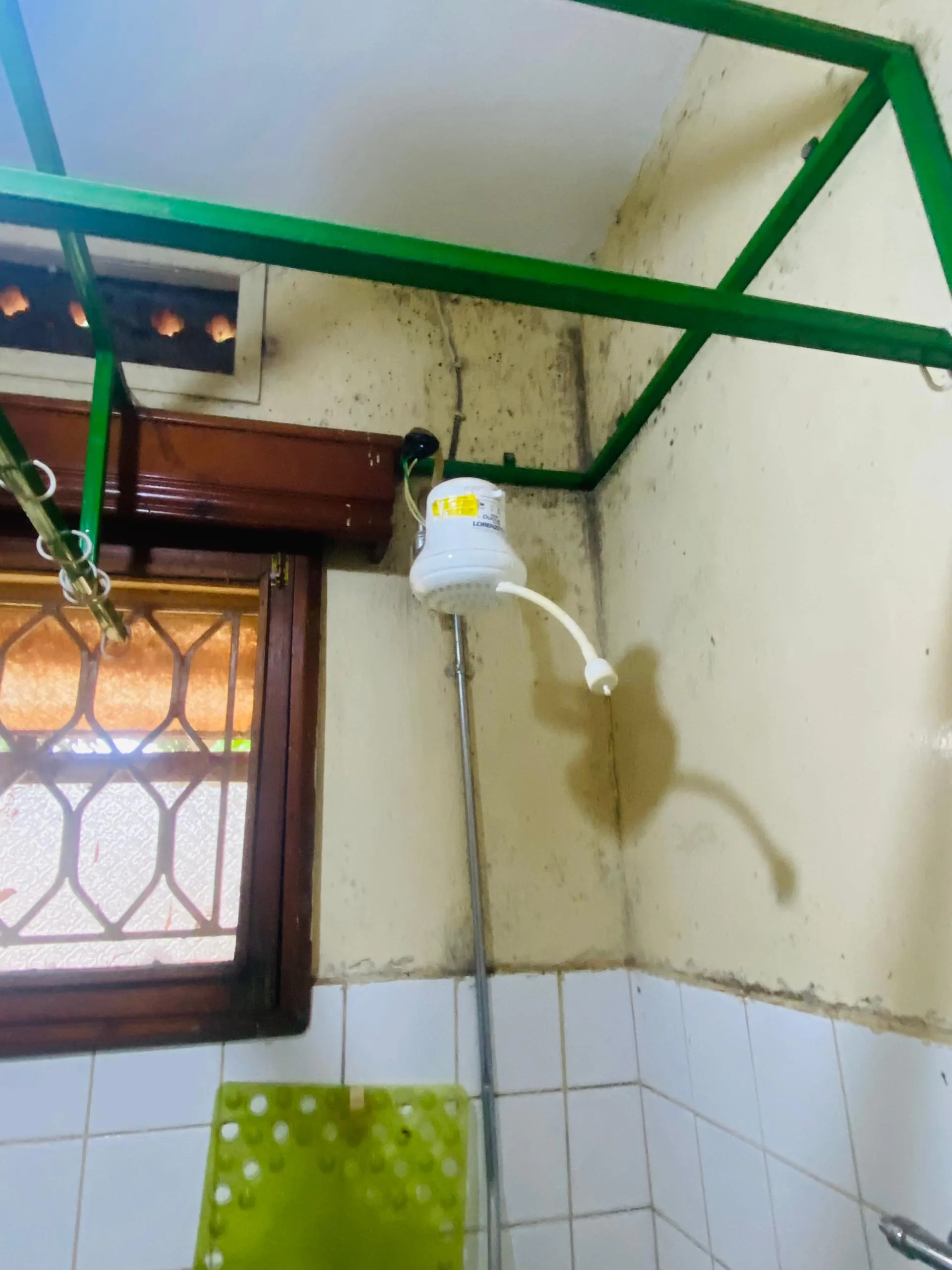 Deteriorated electric shower head with mold damage before renovation at Xavier House Nsambya