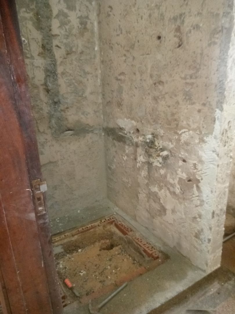 Gutted bathroom showing new green PPR plumbing pipes installed against bare concrete walls