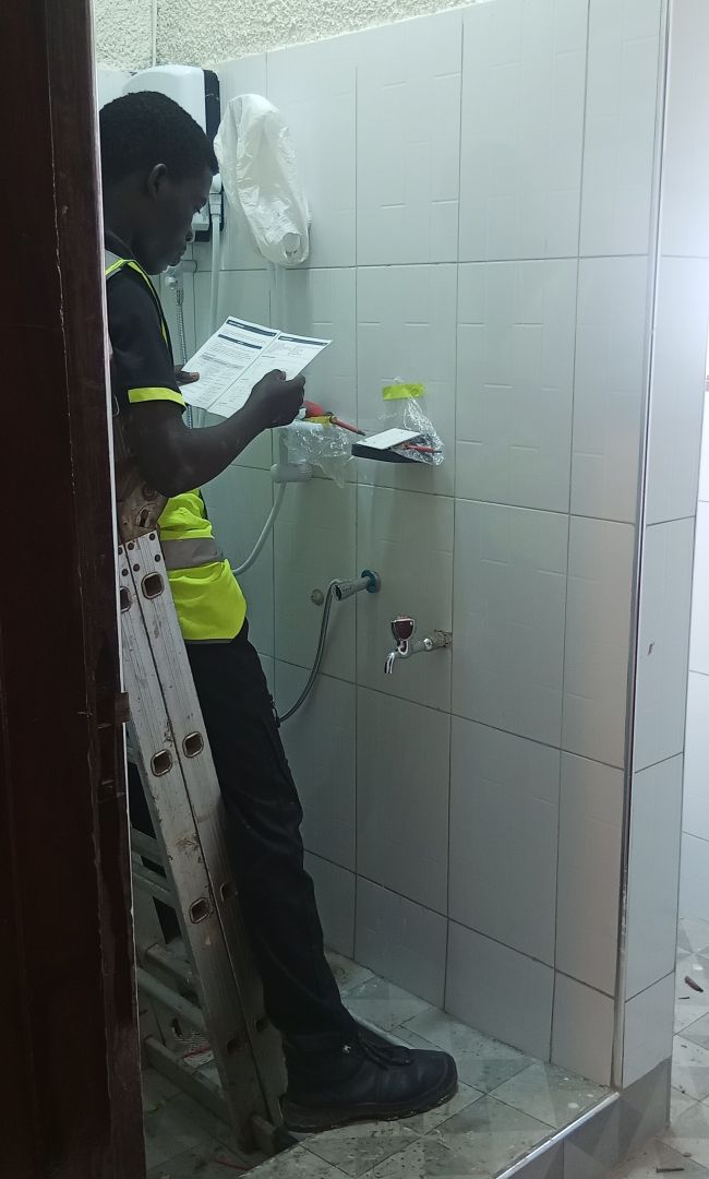 Worker inspecting water heater installation in nearly completed bathroom renovation